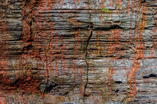 Lava forms knotted basalt with rusty highlights inside Raufarholshellir, Iceland. Rounded ridges cross shadowed gaps, exposing contorted shapes under subdued cave light across cooled rock.
