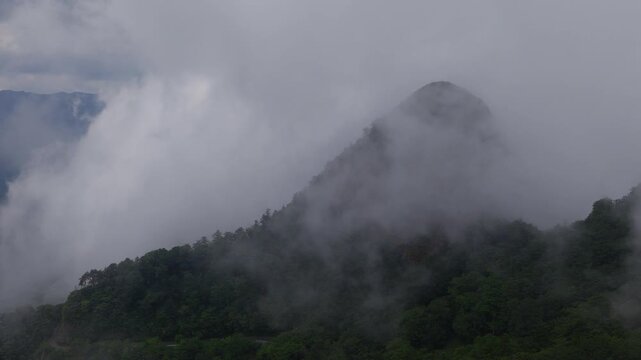 Aerial view of cloud and fog floating over green mountain peak on Shikoku, Japan