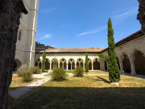 Wide view of the gothic cloister courtyard with twin cypress trees and arched galleries, Gers, La Romieu, France
