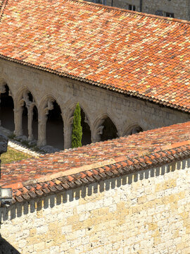 Terracotta rooftops and Gothic cloister arcade seen from above at St. Peter collegiate church, Gers, La Romieu, France