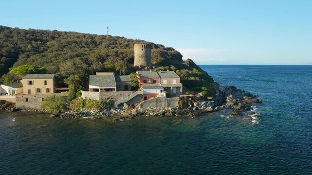 Marine de Meria Corsica drone flyover Genoese tower crescent beach golden hour late afternoon light, authentic village houses, rocky shore sweep, Cap Corse coastal landscape