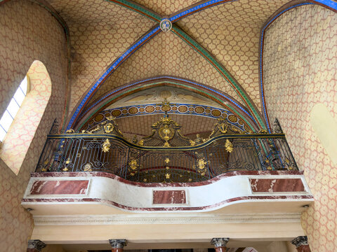 Gilded wrought-iron organ loft balustrade beneath a painted ribbed vault at Saint Mary abbey, Gers, Boulor, France