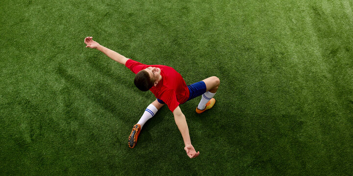 Athlete sliding on pitch during demanding football play. Concept of sliding tackles, defensive commitment, game pressure and athletic effort.