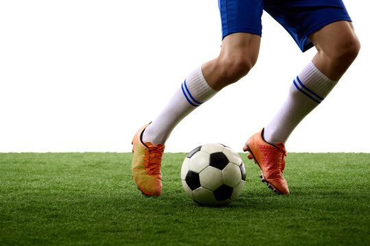 Closeup of soccer boots guiding ball across green turf. Concept of equipment, ball control, footwork instruction and grassroots football training.