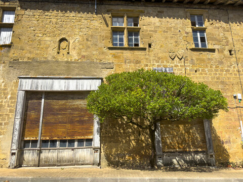 Stone house facade with weathered wooden garage doors and a carv