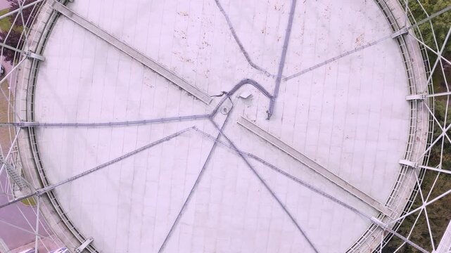 High-angle aerial top view of a large industrial gas holder roof with structural framework and piping for energy infrastructure