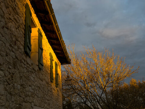 Stone farmhouse facade lit by evening light with wooden shutters, Gers, Saint Georges, France
