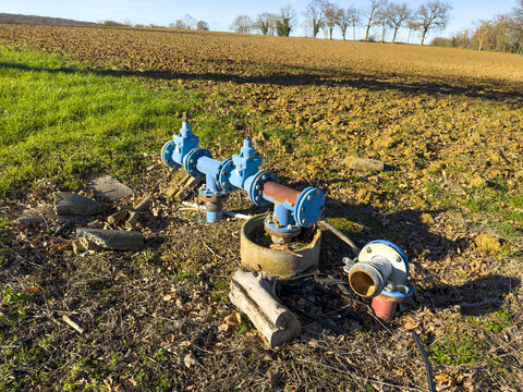 Blue water pipe valves installed at the edge of a farm field, Ge