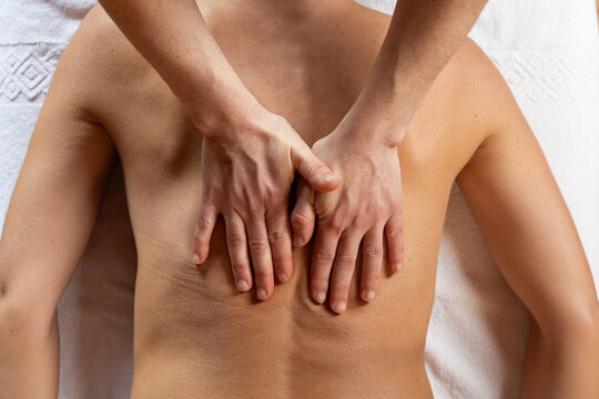 Massage therapist's hands working on a woman's bare back