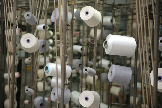 Lahore, Pakistan - 02 October 2024: View of colorful spools of thread and yarn arranged on a textile machine at the Quaid-e-Azam Industrial Estate in Lahore, Punjab, Pakistan.