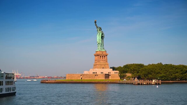 New York, USA, 4 Jule 2026 : Statue of Liberty viewed from passing ferry. Green patina covers the copper monument as a tour boat crosses the harbor beneath a bright sky.