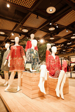 Lahore, Pakistan - 01 October 2025: View of mannequins dressed in colorful traditional Pakistani clothing displayed on wooden platforms inside Packages Mall with modern grid ceiling lighting.