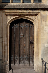 Heavy studded oak door with wrought iron fleur de lis hinges in a gothic arched Bath stone surround. © Victor