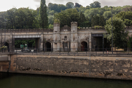 Crenellated gothic revival river frontage with turrets and pointed arches above the River Avon in Bath, Somerset.