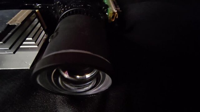 Side angle close-up of a camera lens module with metallic heatsink on dark background