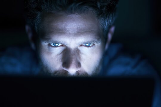 Student browsing on laptop in dark room at night