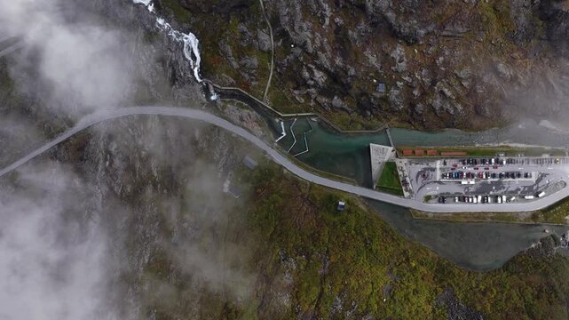 Aerial view of the winding Trollstigen mountain road with its dramatic curves, parking area, and surrounding rugged landscape in Andalsnes, More og Romsdal, Norway.