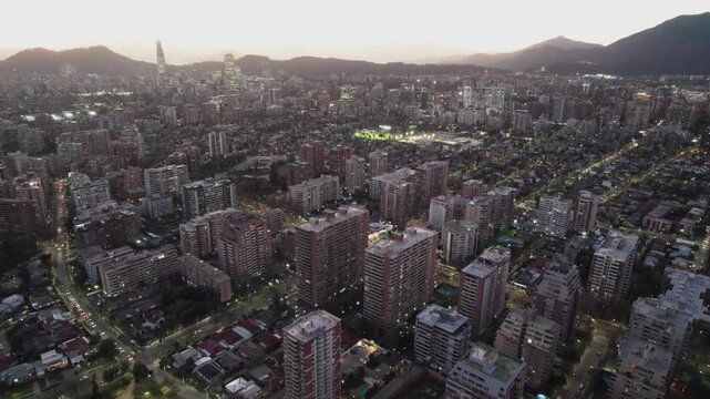 Aerial Drone Descent Over Santiago de Chile Skyline And Lit Buildings At Sunset