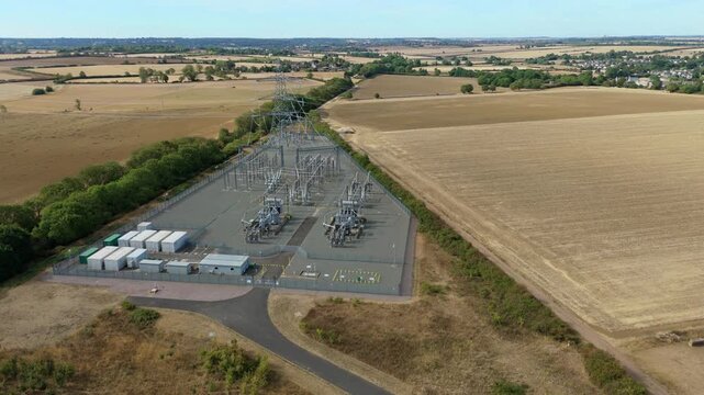 Aerial view of National Grid Ryhall Substation with air cooled transformers and high voltage equipment surrounded by agricultural fields in Ryhall, England, United Kingdom.