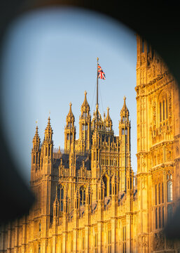 London, United Kingdom - 25 August 2025: View of the Elizabeth Tower and the Palace of Westminster illuminated by warm golden hour light against a clear blue sky.