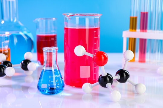 Chemical model of ethanol molecule and laboratory glassware on white table, closeup