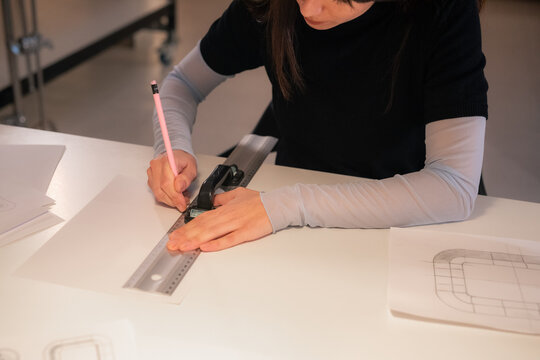Woman using pencil and ruler to draw sketch