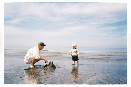 Dad and child building a sandcastle at low tide