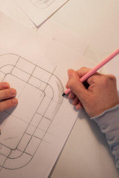 Person Draws a Design on Paper With a Pencil in a Workspace