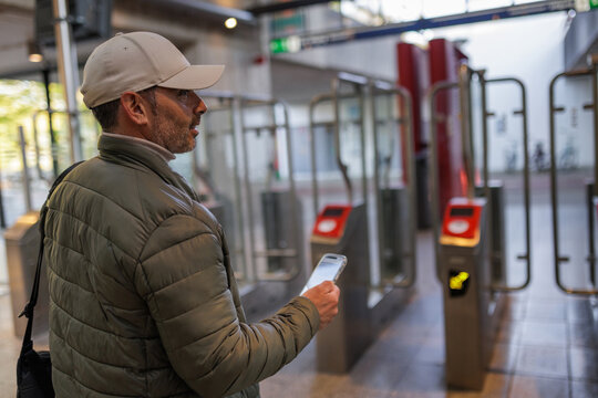 Commuter Using Smartphone at Amsterdam Metro Ticket Gates