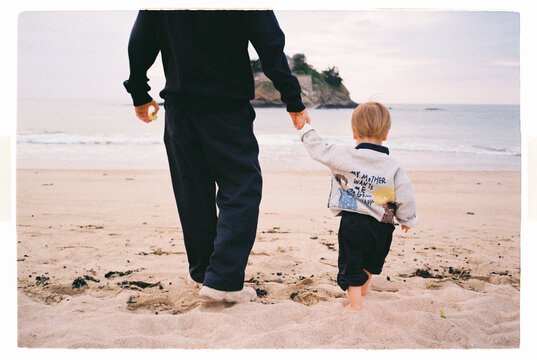 Unrecognizable father and child holding hands on a beach