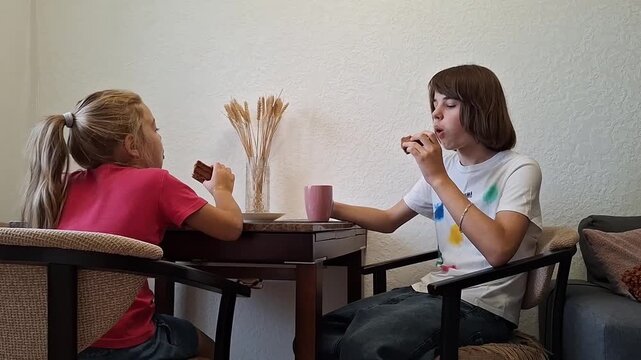 13 year old boy enjoys snack and drink while sitting with a friend in a cozy indoor setting