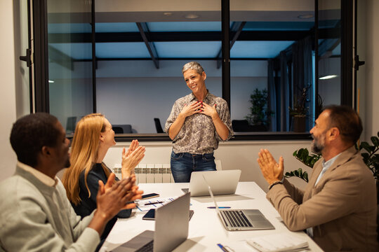 Diverse coworkers applauding colleague in modern office