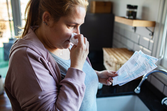 Stressed woman reviewing household bills in kitchen
