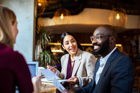 Smiling coworkers reviewing reports at cafe