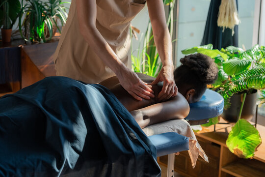 Therapist kneading back muscles of client at wellness centre