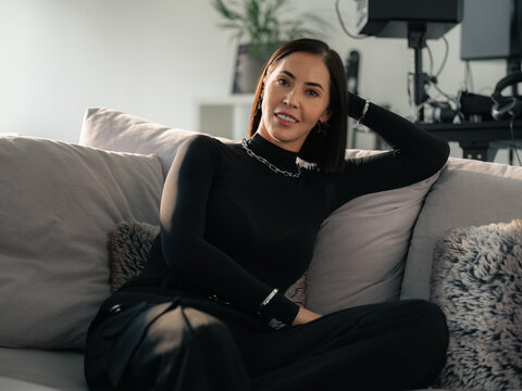 Woman Sitting on Sofa in Modern Living Room With Music Equipment