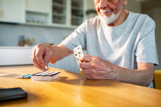 Senior man organizing medication in home kitchen