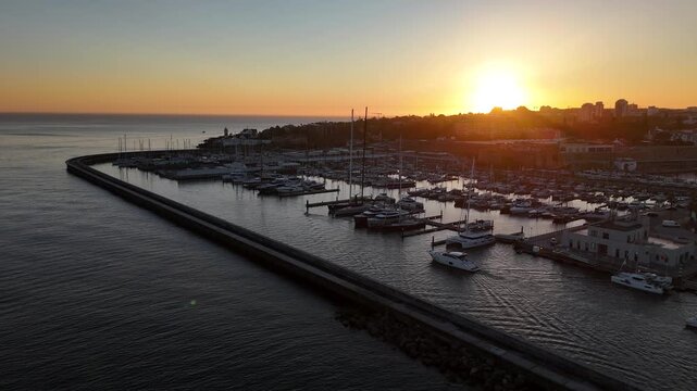 Aerial view of Marina de Cascais with boats docked in the harbor during a golden sunset in Cascais, Lisboa, Portugal.