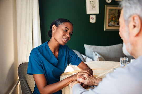 Female nurse comforting senior man at home