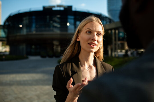 Businesswoman talking with colleague outdoors in modern city