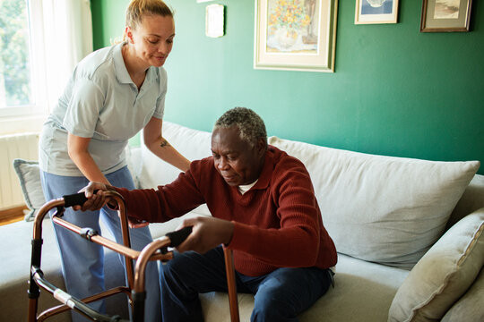 Caregiver assisting senior man with walker at home