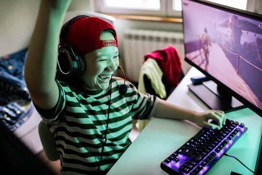 Happy teen gamer celebrating win at home desk