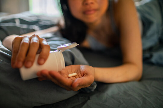 Woman taking pill while lying in bed at home