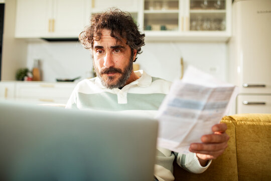 Man reviewing bills on laptop at home