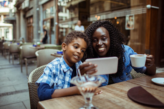 Mother and son using smartphone at outdoor cafe