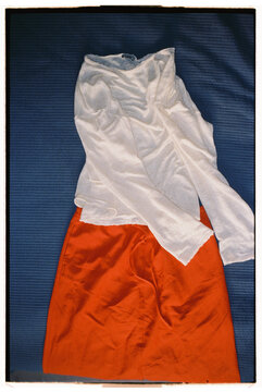 Red skirt and white shirt laid out on blue fabric