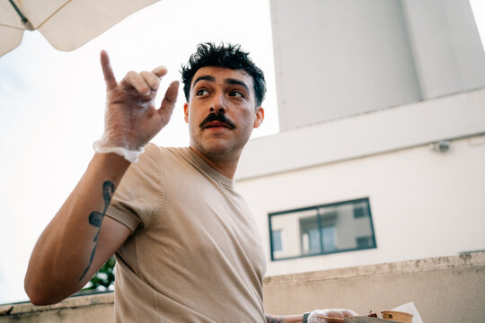 Man Talking While Holding a Food Container on a Rooftop in the City