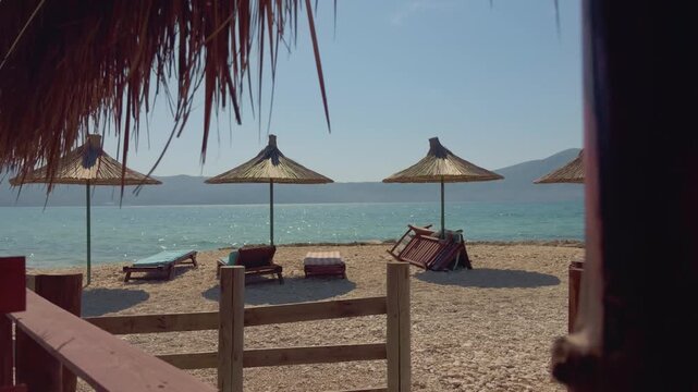 Straw Umbrellas And Sunbeds On Sandy Sea Beach. Empty Tropical Resort Coastline. Coast Vacation 