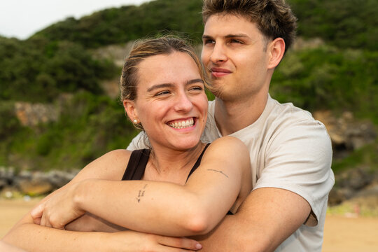 Couple Smiles While Hugging on a Beach During Sunset