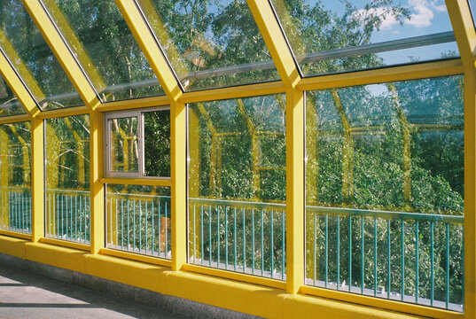 Sunlight streams through a glass walkway with yellow frames